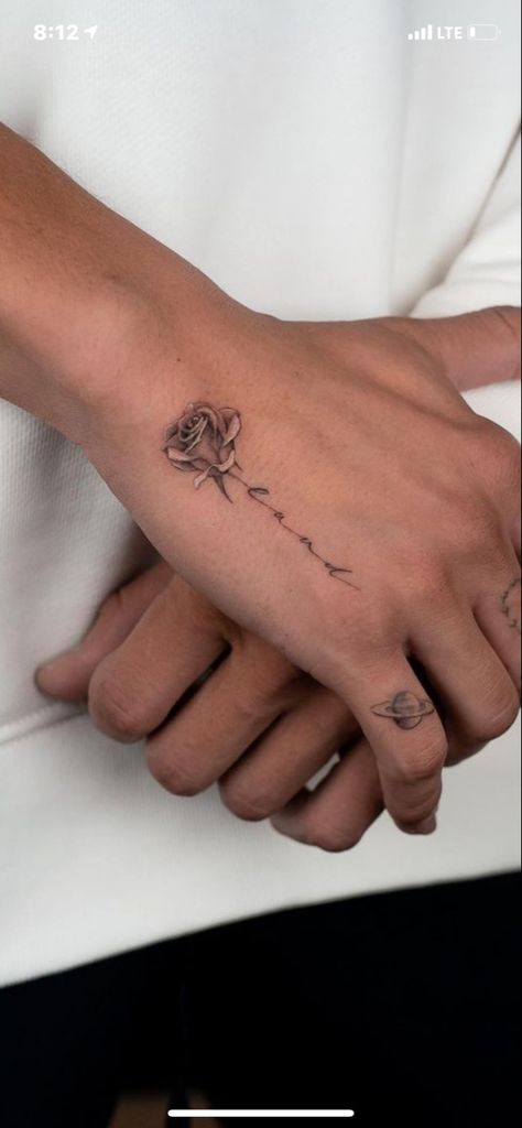 Small Rose Hand Tattoo Woman, Wrist Tattoos For Women Names, Delicate Rose Tattoo Forearm, Rose Into Name Tattoo, Tattoo Dedicated To Husband, Trend Tattoo, Wrist Tattoos For Women Rose, Flower Hand Tattoo With Name, Rose Writing Tattoo