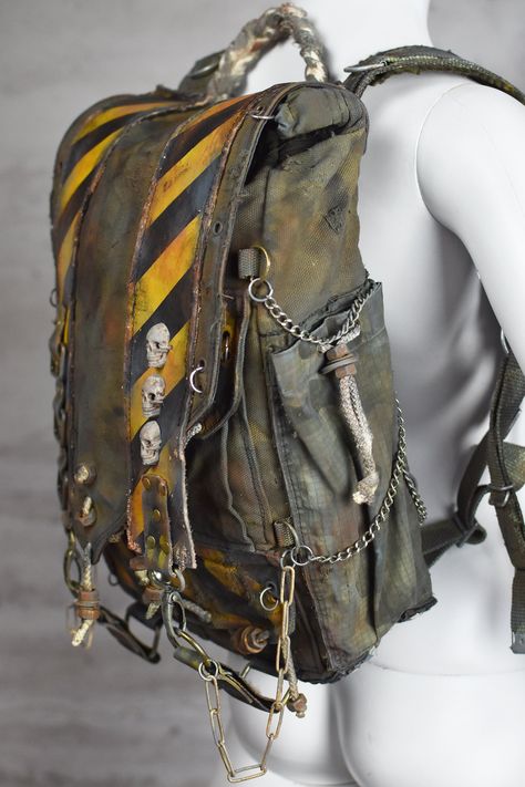 Post Apocalyptic Bag - Postapoc Backpack - Military Rucksack - Camouflage Package - Wasteland Weekend - Burning Man - LARP Accessory Pack Get ready for the post-apocalyptic world with this military green backpack made from waterproof army canvas.  Adorned with yellow biohazard stripes, skulls, and chains, this backpack is perfect for those with a unique sense of style. It features two side pockets, two pockets under the flap, and a drawstring main compartment. There's also a small zipper pocket at the back for added security. With plenty of attachment points, you can easily carry everything you need for your next adventure. Whether you're exploring a desolate wasteland or just commuting to work, this backpack is sure to turn heads. The backpack has a reinforcement at the back and has a spe Post Apocalyptic Decoration, Wasteland Outfit Men, Wasteland Aesthetic Clothes, Dystopian Accessories, Apocalyptic Aesthetic Outfits, Post Apocalyptic Outfit Male, Apocalypse Aesthetic Clothes, Desolate Wasteland, Post Apocalyptic Accessories