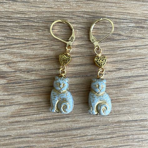 Handmade Czech Glass Gray Cat Bead Earrings Have Gold Celtic Heart Beads Approximately 1.75” Gold Plated Lever Back Ear Wires Silvery Gray Czech Glass Cat Beads Have Gold Features And Trim Tiny Gold Plated Hearts Have A Celtic Knot On Them Handcrafted By Me Gift Boxed, Ready To Wrap My Earrings Always Have $4.99 Shipping! I Always Ship Same Day Or Next Business Day Custom Orders Are Always Welcome Any Questions, Please Ask! Save $$ Bundles Of 2 Or More Items Automatically Receive A 20% Discount! Czech Beads Jewelry, Cat Beads, Pom Crafts, Czech Glass Jewelry, Celtic Heart, Glass Cat, Cat Bead, Casual Earrings, Gray Cat