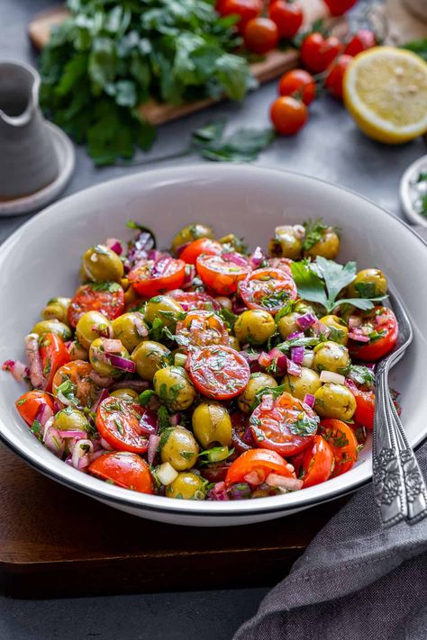 Discover the vibrant flavors of this refreshing Green Olive Salad, packed with fresh ingredients like tomatoes, onions, and herbs. This healthy and delicious salad is elevated by a tangy dressing made from lemon juice, sumac, and pomegranate molasses. Perfect as a side dish, light lunch, or potluck favorite, you'll love how the unique combination of ingredients creates a satisfying and unforgettable taste experience! Tomato Olive Salad, Tomato And Olive Salad, Light Side Salad, Green Olive Recipes, Green Olive Salad, Unique Side Dishes, Santa Cupcakes, Fancy Salads, Vegetables Salad