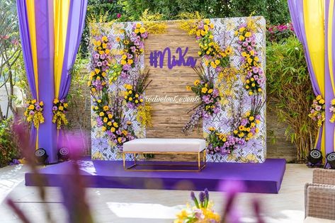 Charming purple with yellow and white backdrop by Red Velvet Events-Dubai. #mehendi #mehendidecor #mehendiseating #indianwedding #wedding #weddingdecor #indiandecor #southindianwedding #haldidecor #hindubride #teluguwedding #tamilwedding Engagement Arrangements Ideas, Haldi Photo Booth, Wedding Backdrop Ideas Diy, Engagement Arrangements, Backdrop Ideas Diy, Flower Wedding Backdrop, Lilac Decor, Haldi Decoration Ideas, Haldi Ceremony Decorations