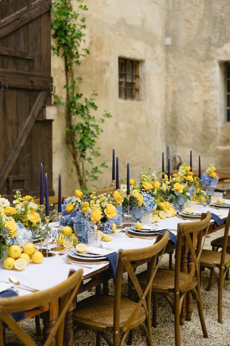 The contrasting colors of blue and yellow florals by Eventfloristin Beate Lohner-Spohn gently stood out amidst the courtyard of the castle. Vows were exchanged in front of a small courtyard pond with a delicate fountain. Pastel Yellow Table Setting, Lemon Inspired Wedding, Lemon Blue Wedding, Tuscany Wedding Table Decor, Yellow And Blue Table Decor, Italian Lemon Wedding Theme, Blue Yellow Wedding Decor, Yellow And Blue Wedding Decorations, Light Blue And Yellow Wedding Theme