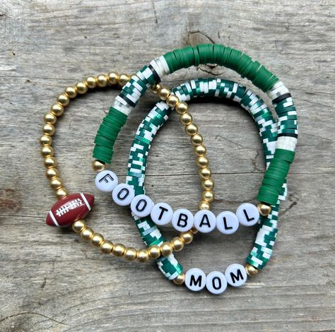 These are fun bracelets that are personalized perfectly for you! This stack is a set of {3} bracelets. The set includes two Heishi disc bracelets (the words can be changed) & a gold bracelet with a ball bead on it.  I change the bead color to match your school/team colors. I will also change the 'football' bead to whichever sport you choose. These stacks can be personalized, and bracelets added. You can reach out to me with any questions or personalization ideas! If you want bracelets added, rea Diy Team Bracelets, Sports Teams Clay Bead Bracelets, Clay Bead Bracelet Ideas School Spirit, School Color Clay Bracelets, Football Bracelet Diy, Heishi Bracelet Stack Ideas, Football Mom Bracelet, Clay Bead Bracelet Ideas Football, School Spirit Beaded Bracelets