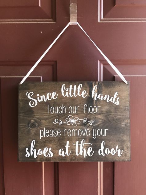 "Shouldn't the friends who visit your home kick their shoes off and get comfortable? Yes! Especially since you have little hands touching your floor. Remind your friends and family to relax and protect your precious little one at the same time with this handmade sign. Since Little Hands Touch Our Floor Please Leave Your Shoes At The Door  Sign Details: --9.25\" x 13\" Wood Sign --3/4\" thick --Dark Walnut Stain Shown (optional change) --White Vinyl Lettering  --White Ribbon Signs may vary in col No Shoes Sign, Remove Shoes Sign, Shoes Off Sign, Baby Room Signs, Remove Shoes, Please Remove Your Shoes, Remove Your Shoes, Welcome Signs Front Door, Front Door Entryway