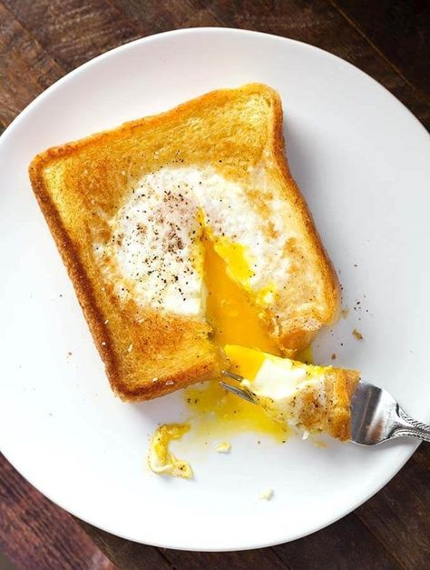 Egg in a Hole is a delicious piece of toast that has an egg soft cooked in the center, which has been cut out. This popular breakfast has many names, like Toad in a Hole, egg in a frame, egg in the basket, but this egg in toast recipe is delicious no matter what you call it! simplyhappyfoodie.com Dropped Eggs On Toast, Eggs In Bread Hole Recipes, Egg In A Hole Skillet, Toast With Egg In The Middle, Eggs In A Hole, Egg Toast Breakfast, Simply Happy Foodie, Egg In A Hole, Over Easy Eggs