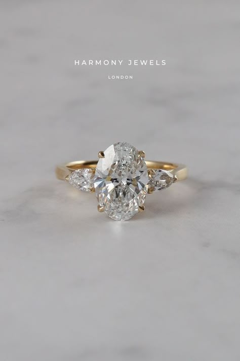 Side Stone Wedding Rings, Harmony Jewels London, Oval Ring With Accent Stones, 3 Stone Oval Engagement Ring Yellow Gold, Oval With Trillion Side Stones, Oval Diamond Side Stones, Oval And Pear Trilogy Engagement Ring, Oval Engagement Ring With Triangle Side Stones, Oval Ring Pear Side Stones