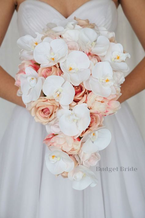 This lovely assortment of roses in a pink champagne color, with pink peonies and white orchids is bound to turn heads on your wedding day. This lovely cascading brides’ bouquet from the Sophie collection is an absolutely breathtaking arrangement for any bride to be, in any season. The stunning white orchids complete the look and add a delicate realism to this beautiful bouquet. This bouquet is 10” wide, 18” long, and is crafted by our in-house florists without using a foam base to anchor the flo Peony Rose Orchid Bouquet, Pink Cascade Bouquet, Wedding Bouquets Without Roses, Wedding Bouquets Orchids And Roses, Beach Pink Wedding, Orchid Arrangements Wedding, Roses And Peonies Bouquet, Elegant Theme Wedding, Rose And Orchid Bouquet