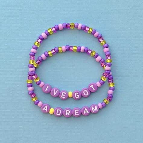 I've Got A Dream bracelet set! This set does not come with the Rapunzel daisies bracelet and the video is just to show what it looks like stacked together :) *You can find the daisy bracelet here: https://www.etsy.com/listing/1744806759/ Handmade with love using Czech glass beads, purple and white letter beads and stretch cord. Get creative! All my bracelets are meant to be mixed, matched & stacked!  SIZING: Measure your wrist around the widest point and add .25-.5 inches to get the most comfortable or desired fit. If you don't have a flexible tape measure, you can use a piece of string to wrap around your wrist and then measure the length of the string. (For example: my wrist size is 6" and I will wear a 6.5" bracelet for a snug fit and 7" for a loose fit). CARE INSTRUCTIONS: Please be ca Disney Inspired Bracelets Diy, Disneyland Bracelets, Disney Bracelet Ideas, Disney Friendship Bracelet, Bracelet With Letters, Disney Friendship, Disney Beads, Disney Bracelets, Pony Bead Bracelets