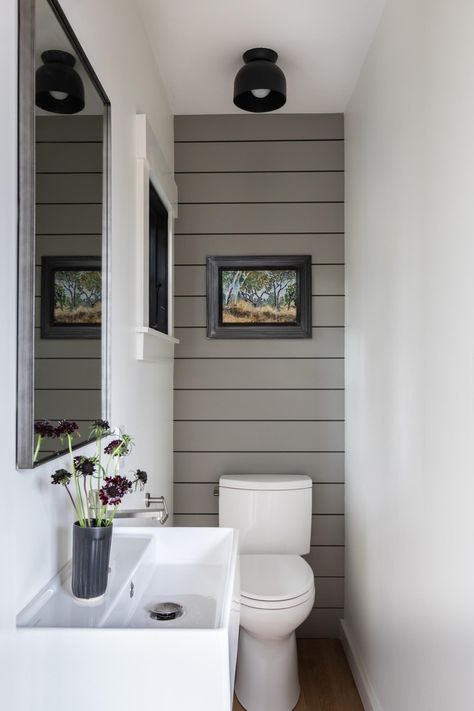 A small powder room with gray wall paneling and a small window for extra light. Tiny Powder Rooms, Powder Room Lighting, Small Downstairs Toilet, Bathroom Under Stairs, Powder Room Remodel, Toilet Room Decor, Small Toilet Room, Powder Room Decor, Downstairs Toilet