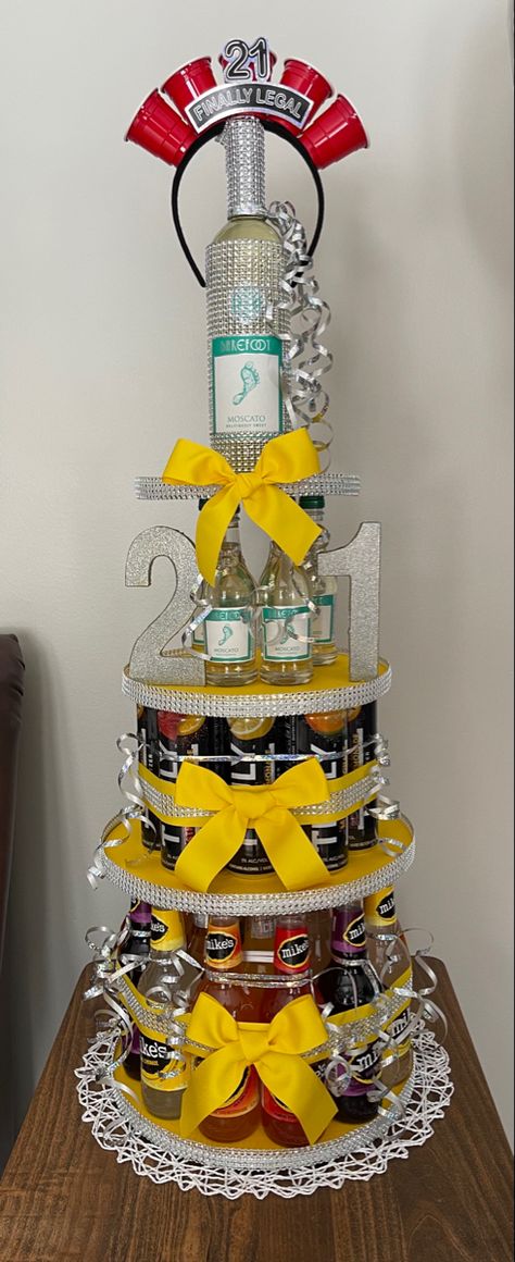 21st birthday alcohol tower four tiers decorated with silver gems and yellow bows. Truly Cake Tower, 21st Alcohol Tower, Drink Cake Tower, 21 Alcohol Cake Tower, Booze Cake Tower, Yellow 21st Birthday Ideas, Shot Cake Ideas, Beer Bottle Cake Tower, 2 Tier 21st Birthday Cake