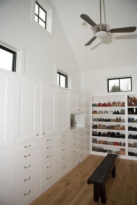 Walk in closet features a cathedral ceiling and windows over built-in wardrobe cabinets stacked ... Tall Ceiling Closet, Glass Wardrobe Doors, Floor To Ceiling Wardrobes, Transitional Closet, Closet Features, Glass Wardrobe, Built In Dresser, Cupboard Wardrobe, California Closets