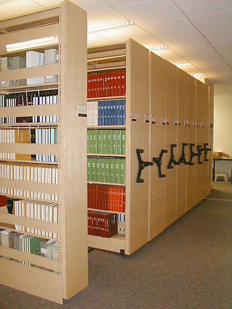 High Density Library Shelving for storage of books and other library media. High Density shelving condenses providing a moveable aisle for multiple access points while using a smaller storage footprint for storing library collections. Movable Bookshelf, Archive Room, Shelving For Storage, High Density Storage, Library Shelving, Library Cabinet, Compact Furniture, Mobile Shelving, Medical Business