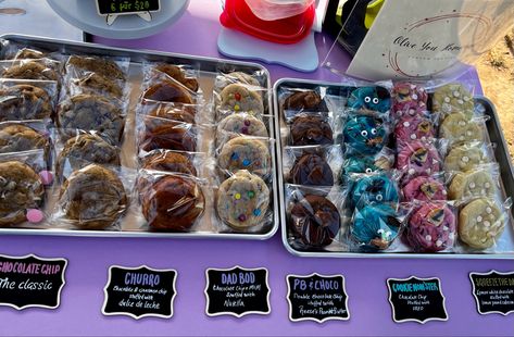 Cookies displayed at a farmers market on silver sheet pans in rows with chalkboard labels Farmers Market Cookies Display, Baked Goods Market Stall, Baking Vendor Booth Ideas, Easy Food Vendor Ideas, Cookie Popup Display, Cookie Stall Display Ideas, Cookies Farmers Market, Baked Goods Vendor Booth, Snacks To Sell At Farmers Market