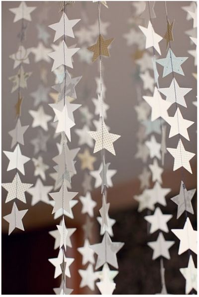 DIY Hanging Stars - we can do these slightly differently (larger stars (~4"), fewer per garland, double the stars so don't see string) hanging from light boxes in main room. kite string is about right weight. light weight card stock - cream on cream print? Deco Nouvel An, Joulun Aika, Diy Jul, Paper Snowflake, Star Garland, Navidad Diy, Star Party, Star Wars Party, Paper Stars