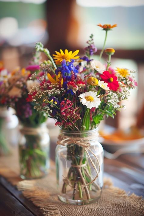 Discover the perfect blend of simplicity and elegance for your big day! 🌼💐 Our DIY wedding centerpieces feature vintage mason jars, handpicked wildflowers, and natural twine accents. Create a cozy, romantic atmosphere at your reception. #WeddingInspiration #RusticWedding #DIYBride #MasonJarDecor #WildflowerCenterpieces #VintageWeddings #SimpleElegance #RomanticDecor Wildflower Table Arrangements Wedding, Rustic Spring Wedding Centerpieces, Wedding Table Wildflowers, Wildflower Farm Wedding, Summer Wedding Wildflowers, Cute Wedding Themes Ideas, June Garden Wedding, Wildflower Arrangements Simple, Whimsical Garden Wedding Centerpieces