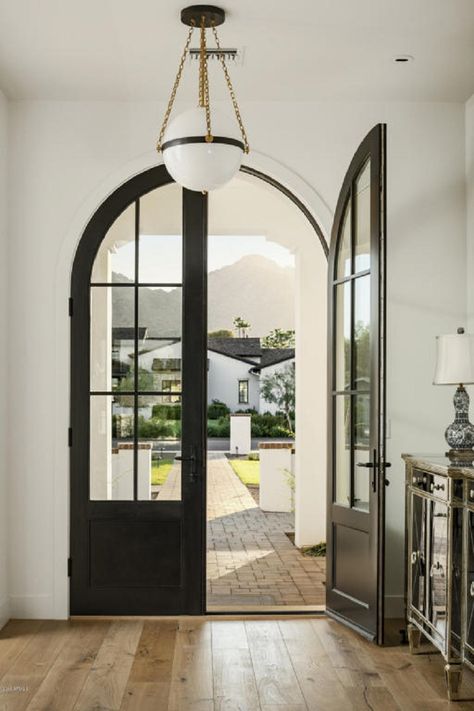 The matte black finish of the grand Aluminum Clad, arched front door makes quite a statement. The window panels on the door allow the warm, natural light to flow through. @Hoppe Verona Escutcheon door lever Arched Doorway Exterior, Arch Door Entrance, Arch Front Door, Arc Door, Custom Front Entry Doors, Metal Front Doors, Arched Front Door, Arch Door, Black Front Doors