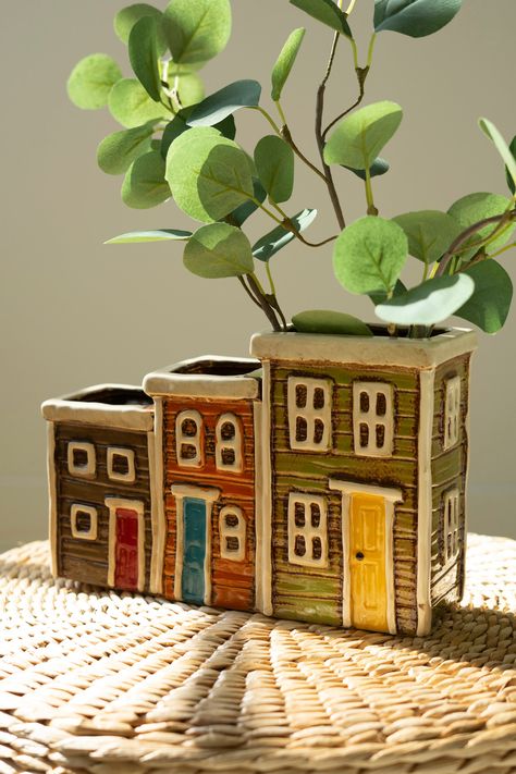 This ceramic village planter features three tiered houses in a row with room for blooms, pencils, or other essentials. This colorful trio is a great addition to your desk or mantle, or anywhere you need a sprig of something new. Grab a set to use as bookends or a gift to the realtor in your life. Ceramic Imported Brand: Kalalou Ceramic Vase Display, High School Clay Projects Ceramic Art, Handmade Pottery Vases Clay, Ceramic Mail Holder, Slab Ceramics Projects, Cute Ceramic Projects, Ceramic Houses Ideas, Unique Clay Projects, Handmade Ceramic Gift Ideas