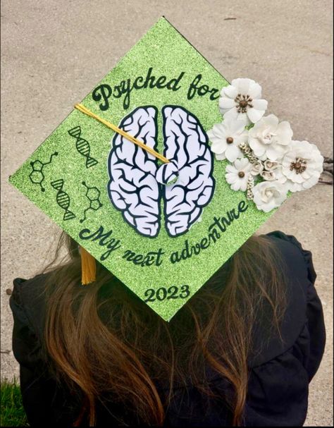 College graduation cap topper. Green glitter background with a brain in the middle. One side features molecules and the other side is flowers. Text on the cap says “psyched for my next adventure” with the graduation year on the bottom Bachelors In Psychology Cap, Graduation Caps For Psychology Majors, Cap Decoration Graduation College Psychology, First Gen Cap Ideas, Psychology Senior Pictures, Psychology Degree Photoshoot, School Psychology Graduation Cap, College Graduation Pictures Psychology, Grad Cap Designs Psychology