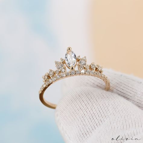 Indulge in regal charm with our Crown-Shaped Vintage Ring, featuring a dazzling marquise-cut white sapphire embraced by genuine diamonds. This exquisite piece exudes timeless elegance and vintage allure, making it a captivating addition to your collection. F E A T U R E S 💎 D I A M O N D Carat: 0.30 Quality: VS1 Color: F-G Cut: Round 💠 G E M S T O N E Type: White Sapphire Carat: 0.25 Cut: Marquise 🌟 M A T E R I A L Gold: Available in 14K and 18K Options Color: Choices of White, Rose, or Yello Dainty Rose Gold Promise Ring, Engagement Ring Crown, Crown Shaped Rings, Cute Dainty Wedding Rings, Engagement Rings Crown, Crown Engagement Rings, Rings Engagement Dainty, French Wedding Rings, Magic Jewelry Aesthetic