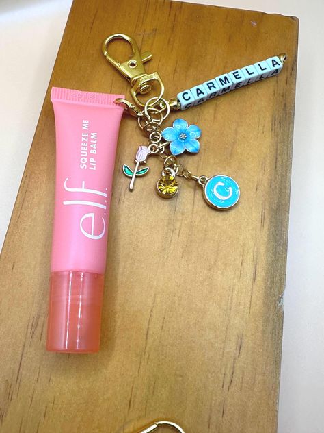 Hey, beauty lovers! Get ready to elevate your lip balm game with our Lip Balm Clip with Charms. This adorable accessory not only keeps your Elf lip balm handy but also adds a touch of personality with its cute charms. Clip it on for convenience and say goodbye to digging through your bag to find your lip balm! Perfect for on-the-go use, this charming clip ensures your lips stay moisturized wherever you are. Stay stylish and never lose your favorite lip balm again with our Lip Balm Clip with Charms! Simply select 3 charms from our options and give me the name you want on the clip! Elf Lip Gloss Keychain, Elf Lip Balm Keychain, Lip Balm Charm, Lip Keychain, Elf Lip Balm, Diy Crafts To Do At Home, Lip Balm Keychain, Pink Lip Balm, Polaroid Picture Frame