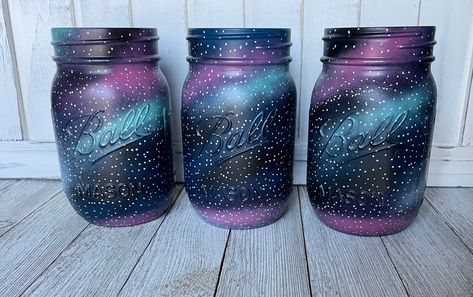 "Pint Galaxy Mason Jar * Perfect for a centerpiece at a galaxy or space themed party or for home decor * Mason Jar is spray painted with layers of spray paint for galaxy effect, then painted with a paint pen for the stars and finished with a protective finishing spray * Jar can come with or without the lid. NO extra charge for the lid * Price is for 1 Pint Mason Jar * Pair with other galaxy items that are also in the shop (pictured above) * Mason Jar Size: 5\" x 2 1/2\" x 2 1/2\" * More Jars can Galaxy Centerpiece Ideas Birthday, Space Decorations Galaxy Party, Galaxy Centerpieces, Space Themed Centerpieces, Galaxy Centerpiece Ideas, Galaxy Baby Shower Ideas, Space Theme Wedding, Space Centerpiece Ideas, Galaxy Themed Room