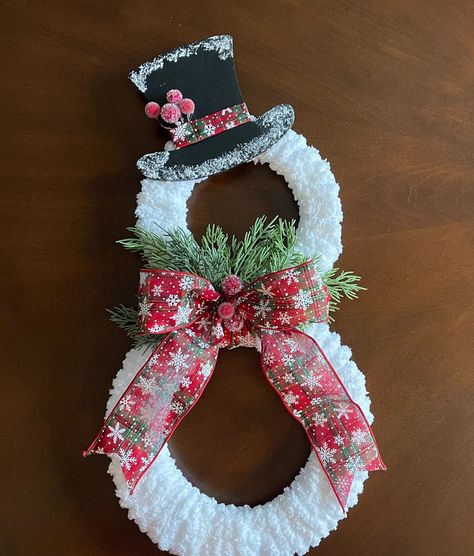 This charming handmade snowman wreath is the perfect addition to your holiday decor! Crafted with soft, fluffy yarn, this wreath mimics the look of freshly fallen snow. The snowman design features a whimsical top hat adorned with frosty detailing and cheerful snowy accents, along with a festive red and green bow decorated with snowflakes. Sprigs of greenery add a natural, wintry touch, completing the snowman's look. Measuring approximately 19 inches tall, this delightful snowman wreath will make a wonderful statement on your front door or as part of your indoor holiday decor. Ideal for welcoming guests, this wreath is a great gift idea or a perfect addition to your own Christmas collection. Display it on your door, between doors, or on a wall to spread holiday cheer all season long. **Prod Christmas Wreath Snowman, Snowman Yarn Wreath, Snowman Wreaths For Front Door, White Christmas Wreaths For Front Door, Snowman Wire Wreath Form, Snowman Wreath Ideas, Pool Noodle Christmas Crafts, Christmas Reefs For Doors, Snowman Wreath Form