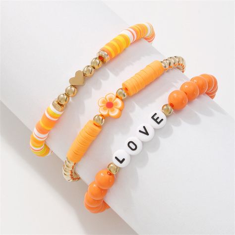 A stretch bracelet set featuring vibrant hues, goldtone accents and a sweet alphabet-letter statement. Includes orange and goldtone text beaded stretch bracelet, orange and goldtone heart beaded stretch bracelet and orange and goldtone flower beaded stretch bracelet (three pieces total) Full graphic text (text bracelet): Love. 0.31'' W Stretch Goldtone copper / acrylic / resin / polymer clay Ankle Bracelets Diy, Beaded Braclets, Preppy Bracelets, Homemade Bracelets, Resin Polymer Clay, Autumn Bracelet, Polymer Clay Bracelet, Orange Bracelet, Bracelet Sets