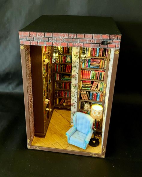 Step into the warmth of a cozy library setting with this handcrafted Library Book Nook. Designed with meticulous detail, this miniature scene brings the charm of a vintage reading room to life, featuring bookshelves lined with classic volumes, a plush armchair, glowing lanterns, and a vintage floor lamp. The wooden flooring and retro wallpaper add an extra touch of elegance, creating an inviting atmosphere for any book lover. Every element is carefully crafted to recreate the intimate ambiance of a charming home library. Perfect for literary enthusiasts, this book nook serves as a unique decorative piece, transforming your bookshelf into a window to a cozy reading corner. Handcrafted Quality:  Lovingly made with top-quality materials, this book nook reflects exceptional craftsmanship. Each Library Book Nook, Unique Bookshelf, Cozy Reading Corner, Bookshelf Insert, Plush Armchair, Unique Bookshelves, Vintage Reading, Cozy Library, Cozy Reading Corners