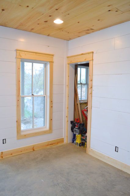 installing DIY shiplap walls and farmhouse trim from wood flooring Simple Wood Window Trim, Farmhouse Living Room Trim, Window Trim No Sill, Natural Wood Window Trim, Simple Farmhouse Trim, Farmhouse Chair Rail, Modern Farmhouse Interior Trim, Burnt Wood Trim, Natural Wood Baseboards