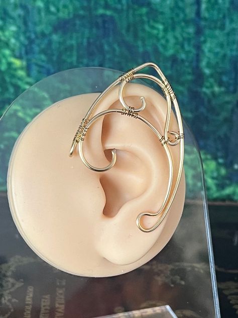 Wire wrapped ear cuffs that come in a set of two, one for each ear.  Made using bendable jewelry wire, the back bar can be bent and shaped to fit any ear size for a comfortable fit.  These babies come in 2 different sizes: -Small -Large Handcrafted ear cuffs help bring out your inner elf ️️  ✨FAQ✨ How soon can I get my cuffs? My normal free shipping included with your order will take between 3 and 5 business days to get to you once shipped out. If you would like to add on the additional expedite Wire Wrap Elf Ears, Renfaire Fairy, Elf Ear Jewelry, Wire Elf Ears, Ear Cuffs Gold, Vtuber Ideas, Elf Earrings, Elf Tiara, Elvish Wedding