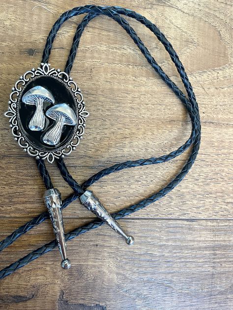 This awesome bolo tie has a solid metal black backing with two silver metal mushrooms in resin. Quality guaranteed, picture does not do this buckle justice! The piece measures 2'' x 1 1/2''. It can adjust lengths, 41'' in total length.   We have matching belt buckles to pair! Big Christmas Gifts, Cowboy Accessories, Food Magic, Vintage Leather Vest, Mens Leather Necklace, Western Gifts, Black Food, Mens Necklace, Gift Inspo