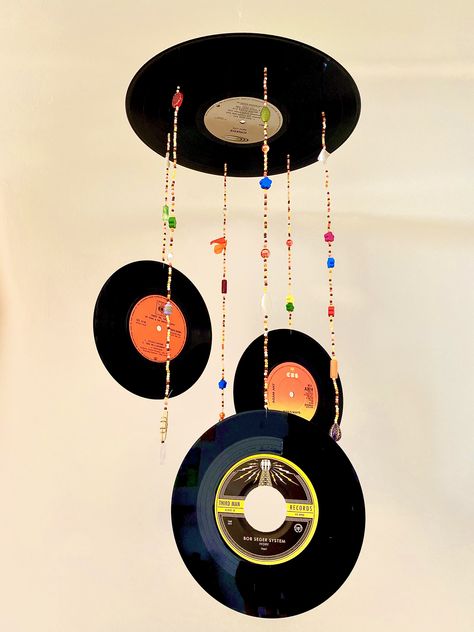 DIY hanging vinyl mobile retro room decor 70’s Crafts From The 70s, Vinyl Hanging Decor, 70s Room Decor Diy, Crafts From The 1970's, Record Hanging Ideas, Vinyl Record Projects Upcycle, Vinyl Record Wind Chime, Retro Room Decor Diy, Hanging Records From Ceiling