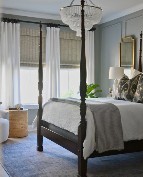 We love a bedroom that exudes a sense of timeless elegance! This bedroom features a wood bedframe, neutral wall paint, and a stunning chandelier that adds a touch of glamour to the space. The neutral blinds and flowing white curtains create a soothing ambiance while the soft rug adds a cozy feel to this inviting haven. Tap the image to see more bedroom design inspiration in our blog post at One Coast Design! Neutral Blinds, Four Poster Bedroom, Colonial Bedroom, Classic Bedroom Design, Dark Wood Bed, Stunning Chandelier, Home Design Magazines, Four Poster Bed, Traditional Bedroom Decor