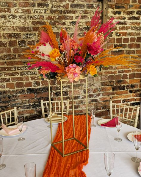 Orange and Pink Wedding Flowers. Set in the beautiful chamblesforth hall and grange. This style was mixed with dried and artificial flowers, and finished with bright pink and orange pampas grass. The table centerpieces were displayed on gold plinths from @kcoevents Added extras finished by the bride 😍 #smallbusinessyorkshire #yorkshiresmallbusiness #weddingcenterpieces #pinkorange #pinkorangewedding #pampascenterpiece #weddingdecor #selby #camblesforthhall #camblesforthhallandgrangewe... Pampas Centerpieces, Dried Flower Centerpiece, Dried Flower Shop, Pink And Orange Wedding, Orange Wedding Themes, Orange And Pink Wedding, Pink Wedding Decorations, Fleur Orange, Wedding Flowers Summer