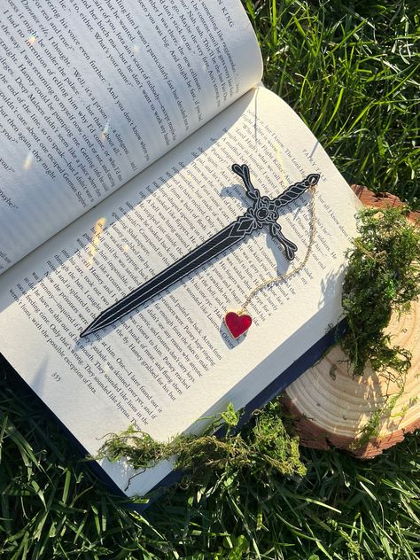 Engraved Leatherette Sword Bookmark, Fantasy Bookmark, Elven-Inspired Bookmark, Gift for Readers, Elf Fairy Faerie Fae Bookmark Make your reading a little extra magical with this beautiful engraved faux leather bookmark with a metal heart tassel. This bookmark is engraved in my home workshop on faux leather leatherette that engraves into a light silver color. HANDCRAFTED IN THE USA- Made in Los Angeles, California by a small, family-owned business NATURAL VARIATION DISCLAIMER- due to the unique nature of the materials we work with, no two items will look exactly the same. There may be slight differences in color, grain, etc that are characteristic of the wood since no two trees are the same. Fancy Bookmarks, Diy Bookmark Ideas, Matching Bookmarks, Faux Leather Bookmark, Make Bookmarks, Bookmarks Ideas, Heart Tassel, Cool Bookmarks, Fantasy Bookmarks