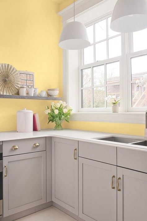 an airy kitchen with light yellow walls, dove grey cabinets and shelves, white pendant lamps and countertops Light Yellow Walls, Yellow Kitchen Walls, White Kitchen Countertops, Blue White Kitchens, Yellow Cabinets, Серая Кухня, Bold Kitchen, Yellow Kitchen Decor, Grey Kitchen Designs