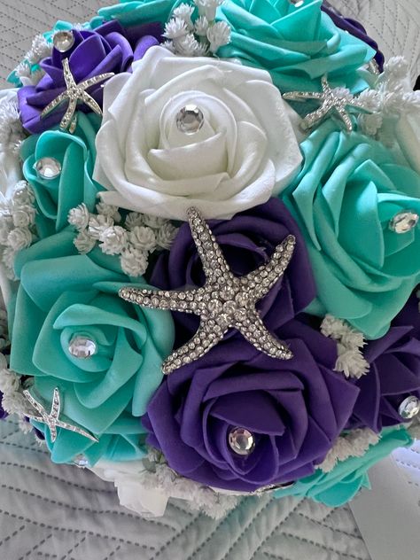 "This bouquet measures 11\" in diameter and 11\" tall. The colors are purple, turquoise and white. Each rose has a rhinestone its center.  There is a large 2\" Rhinestone Starfish brooch in the center as well as pave rhinestone starfish pins scattered around the bouquet.  The blinged handle has a white satin ribbon.   A wonderful addition to your themed event. The real touch roses are terrific if you are having a destination wedding as well. Their shape holds up even if they become squashed in t Mermaid Theme Wedding, Purple Orchid Bouquet, Sea Wedding Theme, Blue And Purple Orchids, Purple Turquoise Wedding, Beach Wedding Purple, Little Mermaid Wedding, Bling Bouquet, Ariel Wedding