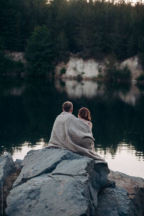 Loving Couple Is Covered With A Blanket Sitting On A Stone In His Career by Demetr White Couple Wrapped In Blanket, Couple Blanket, Couple Laying Under The Stars, Couple Jumping Into Water, Couple Watching Moon Together, Engagement Photos Laying On Blanket, Rock Couple, Couples Blanket, Past Quotes