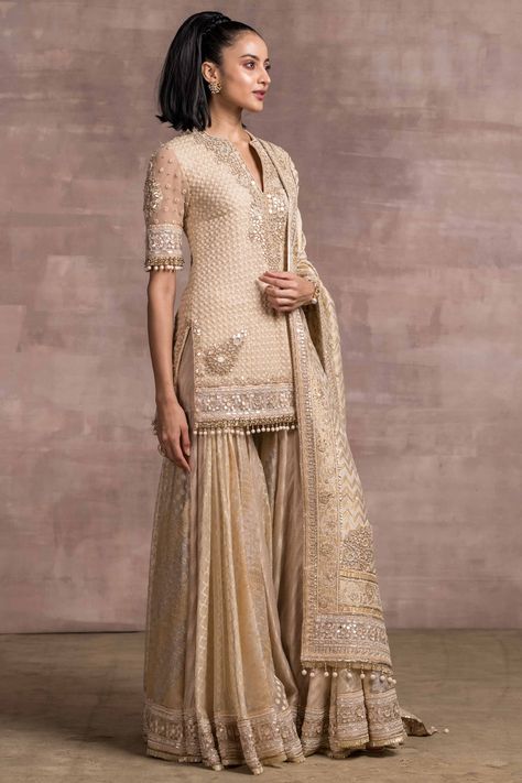 Featuring an ivory and gold kalidar short kurta in silk organza base with fringes and mirror hand embroidery. It is paired with matching sharara pants and a brocade dupatta having pearls, dabka, and tikki embroidery.  FIT: Fitted at bust and waist. COMPOSITION: Silk organza, Brocade. CARE: Dry clean only. Brocade Dupatta, Organza Kurta, Ornate Border, Sharara Designs, Kurta Sharara Set, Kurta Sharara, Indian Outfits Lehenga, Desi Fashion Casual, Tarun Tahiliani