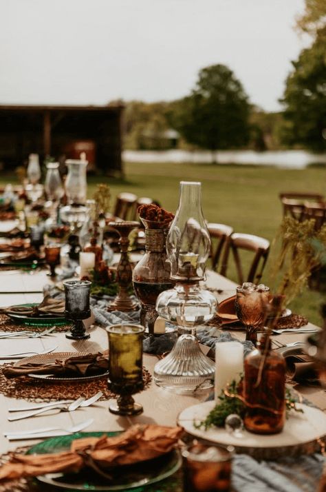 This moody cottage core wedding had the perfect al fresco tablescape! We love the vintage glassware and foraged florals. Check out more outdoor dining ideas on our blog. Boho Thrifted Wedding, October Moody Wedding, Fall Wedding Farmhouse, Bohemian Table Setting Wedding, Vintage Lantern Wedding Decor, Cottage Core Forest Wedding, Boho Antique Wedding, Earthy Wedding Inspiration, Thrifted Wedding Bridesmaid Dresses