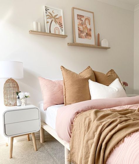 A pretty combination of beige and light pink bedding inspires a light design in this subtle bohemian bedroom. If you display artwork in this type of space, choose images with organic shapes and matching colors to highlight the softness of the room's design. Let simple wood shelves host decorative pieces to enhance white walls. White Apron Sink, Tan Bedding, Colorful Bedroom Design, Fireplace Accent Walls, Bed Frame Sets, Simple Bedside Tables, Dark Countertops, White Subway Tile Backsplash, White Shaker Cabinets