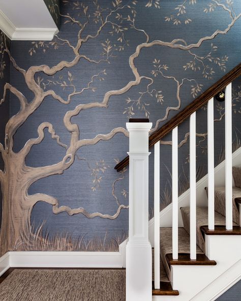 The foyer and main stairwell are high impact and timeless with a striking tree mural that reaches the home's second floor. Painted on a deep blue grasscloth, the tree's design was influenced by an oak tree in a nod to the client's Southern roots. Family Tree Mural, Carpet Staircase, Foyer Staircase, Tree Wall Murals, Staircase Wall, Tree Mural, Family Tree Wall, Chinoiserie Wallpaper, Tree Wallpaper