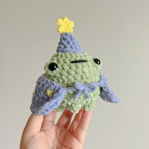 Wizard Froggie Pattern !! 🔮🌱 Skill Level: - Beginner friendly - Basic knowledge of crochet needed. Pattern uses single crochet, bobble stitches, and some sewing.  Materials Needed: - Green, blue, and yellow chunky yarn. Some yellow and black worsted weight yarn.  - 5.00mm and 3.5mm hooks (or two hooks that are 1.5 sizes apart).  - Stuffing - Safety eyes - Needle for sewing, and stitch markers are optional but recommended.  Features: - Simple and easy to read instructions in US crochet terminol Wizard Frog, Frog Crochet Pattern, Frog Crochet, Pattern Magic, Sewing Materials, Cute Frog, Wizard, Pdf Pattern, Crochet Pattern