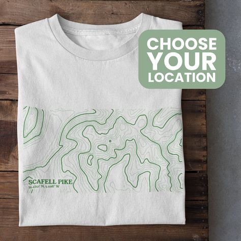 Celebrate your favourite outdoors location with a custom Contour Map T-Shirt! Perfect for any mountain lover, just let us know the location in the personalisation box. We will send you a proof of the design within 1-2 days so you can approve before print! The contour map is designed using online mapping data to make a unique, minimalistic visual that's perfect for an outdoors lover. This Unisex t-shirt is Vegan approved, Gots accredited and Fairwear Foundation certified which makes it a highly eco-friendly product. *Packaging This product is packaged in 100% plastic-free packaging that is compostable and degradable. *Delivery Our products are made to order and aim to have a 7 working day turn around or less for UK orders (Production and Royal Mail First Class Delivery)  Custom orders can t Sustainable Tshirt Design, T Shirt Mountain Design, Contemporary Tshirt Design, Map Tshirt Design, Outdoor Graphic Tees, Outdoor T Shirt Design, T Shirt Design Minimalist, Outdoor Tshirt Design, Simple Graphic Tees