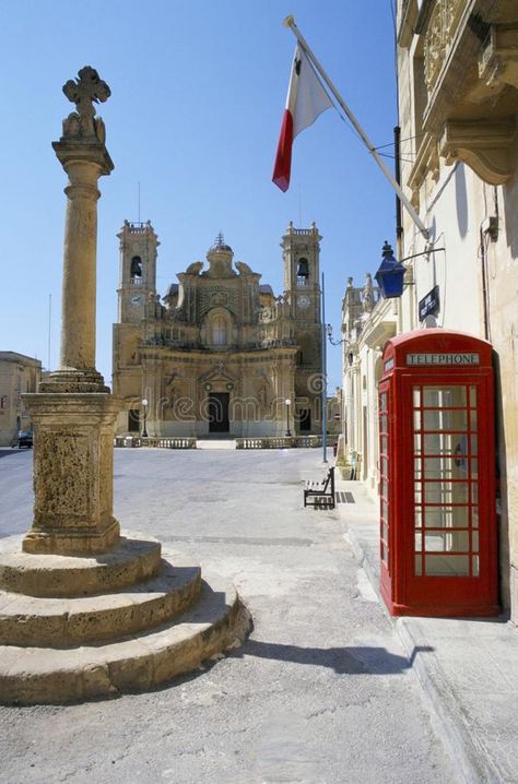 Village Square , Gharb GOZO - Maltese Islands. Village Church with Cross, UK stye telephone box and blue lamp over entrance to police station stock photo Village Square, Maltese Islands, Telephone Box, Blue Lamp, Police Station, Maltese, Malta, Entrance, Photo Image