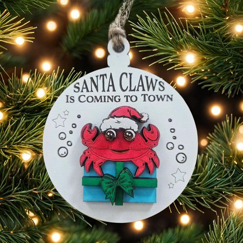 Celebrate the holidays in style with this charming Santa Claws Crab Christmas Tree Holiday Ornament. Crafted with care, this ornament features a cute crab design, perfect for adding a touch of whimsy to your Christmas tree. Whether you're a collector of ornaments or simply looking for a fun and unique holiday decoration, this piece is sure to delight. With its intricate details and high-quality construction, this ornament is a must-have for any Christmas enthusiast. The crab motif is sure to make you smile every time you see it. Add this wonderful piece to your collection today and enjoy its timeless beauty for years to come. Ornament is layered for 3d effect. Ornament measures approx 4" and includes jute cord for hanging. Crab Ornament, Crab Design, Santa Claws, The Crab, New Smyrna Beach, Sea Creature, Santa Ornaments, Holiday Ornament, Holiday Ornaments