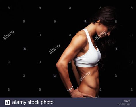 Side view of fitness female model standing with her hands on hips against black background. Muscular young woman. Stock Photo Model Standing, Woman Stock Photo, Hands On Hips, Female Model, Side View, Young Woman, Pose Reference, Face And Body, Black Background