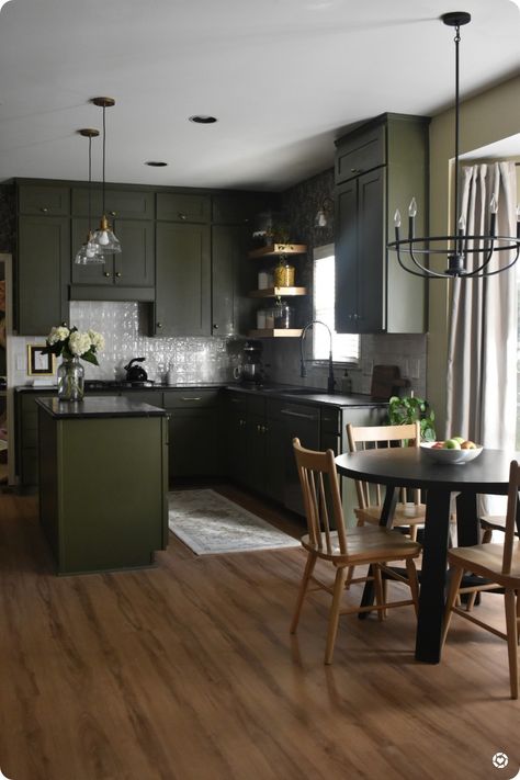 Green kitchen cabinets with light brown LVP flooring. Black chandelier with black soapstone countertops Moody Green Kitchen, Dining Pantry, Lauren Diy, Green Countertops, Moody Kitchen, Moody Green, Dark Green Kitchen, Dark Countertops, Black Countertops