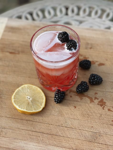 Glass sitting on a cutting board outside filled with a pinky red drink topped with blackberries. Blackberry Moonshine, Moonshine Drink Recipes, Blackberry Drinks, Moonshine Cocktails, Disney Inspired Recipes, Recipes Disney, Sour Drink, Cinnamon Simple Syrup, Disney Drinks