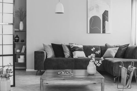 Grayscale photo of a square, wooden table standing in front of a brown, suede sofa with decorative cushions in cozy living room interior Millennial Grey House, Millenial Grey, Millennial Gray, Millennial Grey, Farmhouse Grey, Suede Sofa, Tuscan Villa, Grey Houses, Grey Decor